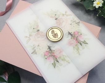 Puede incluir: Un conjunto de invitaciones de boda con un sobre rosa rubor y una superposición de vitela. La superposición está adornada con un diseño floral en rosas y verdes suaves, sellado con un sello de cera dorado. Una cinta de satén añade un toque delicado.
