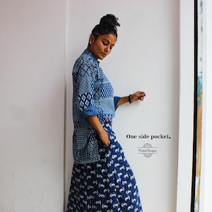 May include: A blue patterned skirt and top set. The top has a geometric design on the sleeves and chest. The skirt has a white pattern on a blue background. The text "One side pocket" is visible.
