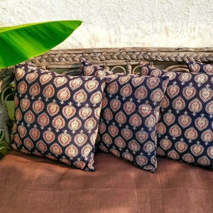 May include: Four decorative throw pillows with a black and white geometric pattern. The pillows are arranged on a brown couch with a woven wicker frame.