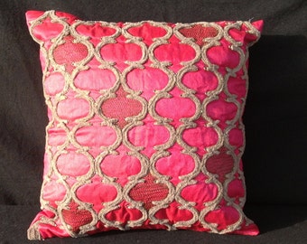 May include: A pink and gold decorative pillow with an intricate geometric pattern.