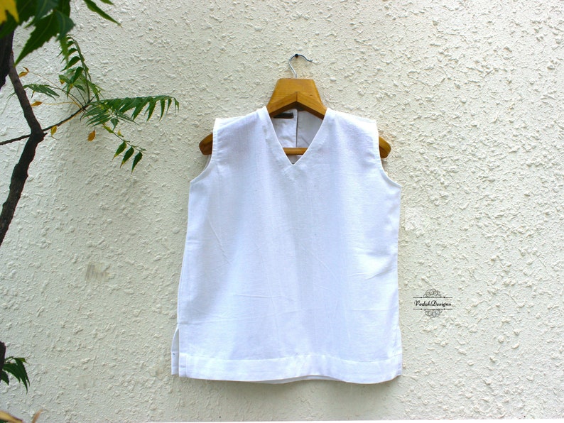 May include: White sleeveless top with a V-neckline. The top is made of a lightweight fabric and has a relaxed fit.