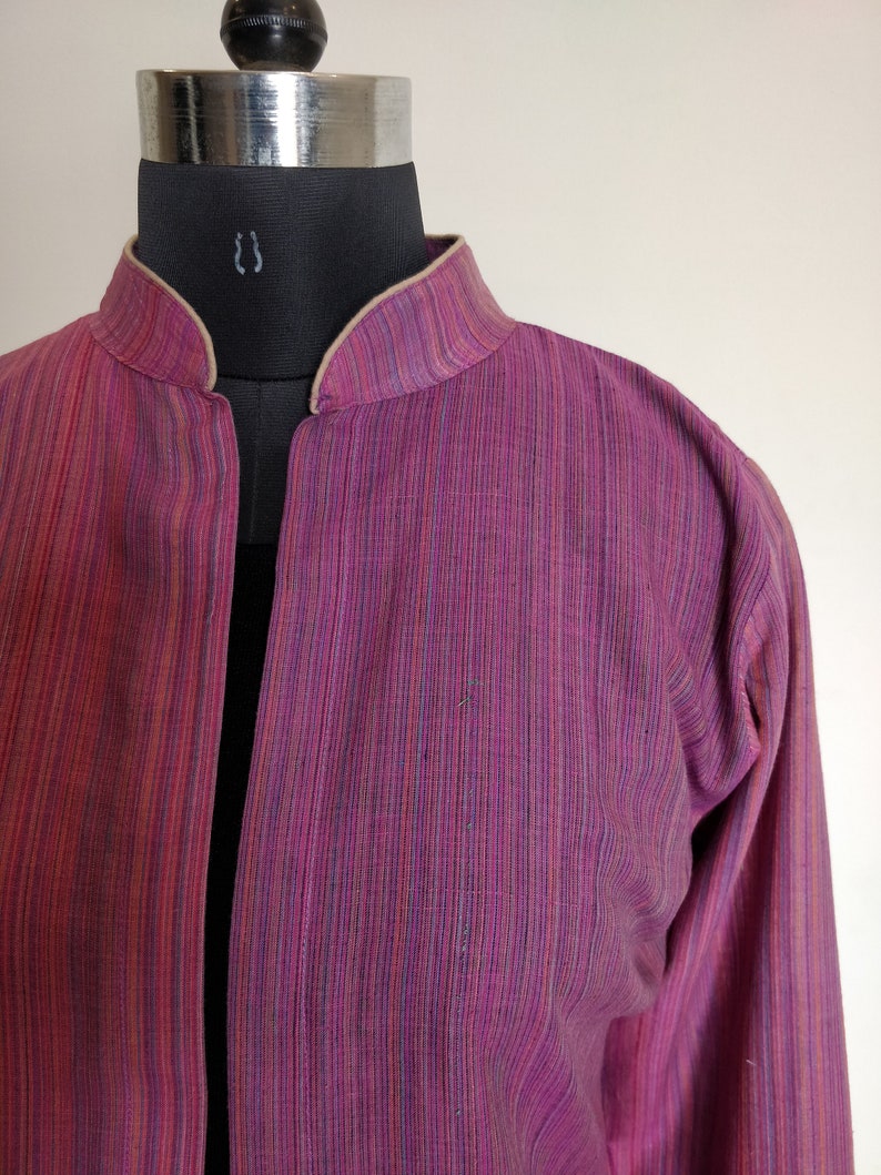 Puede incluir: Una chaqueta de manga larga, de rayas rosa y p&uacute;rpura, con cuello mandar&iacute;n y ribete beige. La chaqueta est&aacute; hecha de una tela ligera y tiene un corte holgado.