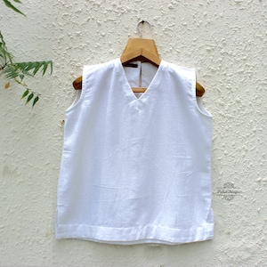 May include: White sleeveless top with a V-neckline and a small label that says "Varda Designs".