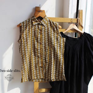 May include: A sleeveless button-down shirt featuring a mustard yellow and white geometric square pattern with a collar, paired with a solid black garment with gathered sleeves. The text "*Two side slits." and "Vedoh Designs" are visible.