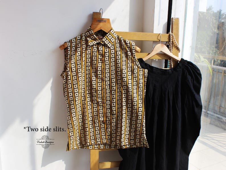May include: A sleeveless button-down shirt featuring a mustard yellow and white geometric square pattern with a collar, paired with a solid black garment with gathered sleeves. The text "*Two side slits." and "Vedoh Designs" are visible.