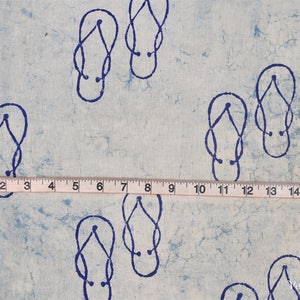 Pode incluir: Tecido azul claro com um padr&atilde;o repetido de chinelos azuis escuros. Uma fita m&eacute;trica mostra um comprimento de 43 cm. O tecido tem uma apar&ecirc;ncia texturizada, com um efeito aquarela.