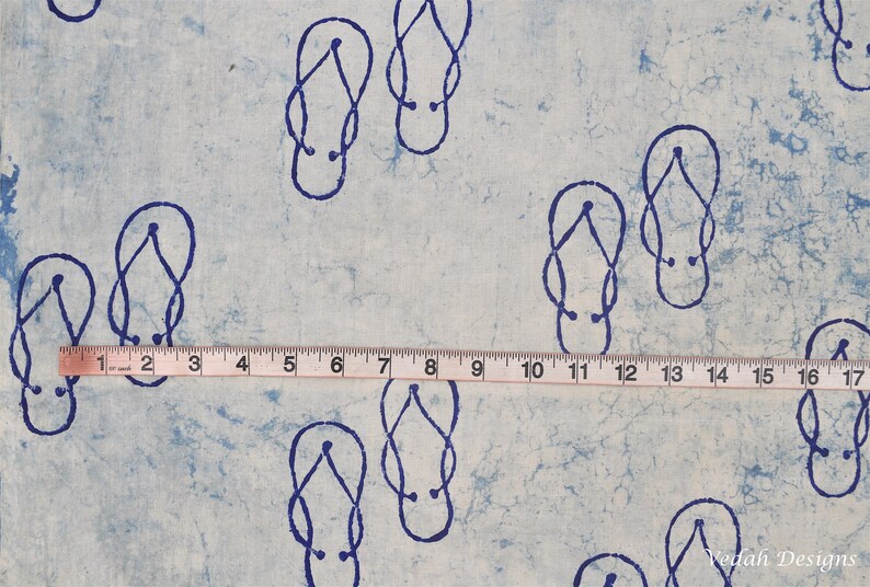 Pode incluir: Tecido azul claro com um padr&atilde;o repetido de chinelos azuis escuros. Uma fita m&eacute;trica mostra um comprimento de 43 cm. O tecido tem uma apar&ecirc;ncia texturizada, com um efeito aquarela.