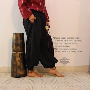 May include: Loose-fitting black trousers with a high waistband and gathered cuffs at the ankles. The garment is paired with a maroon long-sleeved top featuring a white pattern. Text on the wall reads: Please check the size chart (as shown in the last picture.) *For size customization, please message. *No return,no exchange as we customise every order. Vedah Designs.