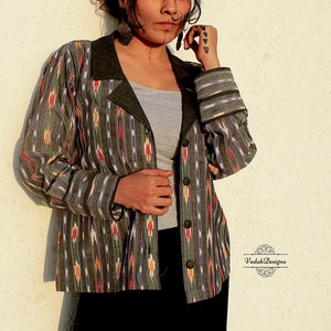 Puede incluir: Una chaqueta de estampado gris y negro con cuello y puños de color verde oscuro. La chaqueta tiene cierre de botones y un diseño a rayas.