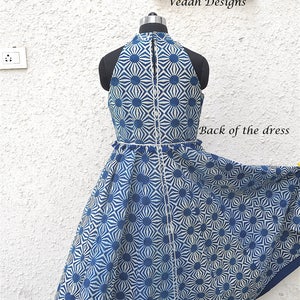 May include: A sleeveless dress featuring a blue and white geometric sunburst pattern, a high halter neckline, and a central vertical seam. The garment is displayed on a mannequin, with the text Vedah Designs and Back of the dress visible.