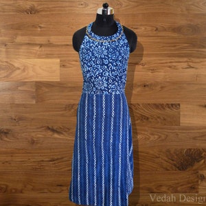 May include: A blue halter dress with a floral and striped pattern. The top section features a floral design, while the lower part has vertical stripes. The dress is displayed on a black mannequin against a wooden background. The dress has a gold beaded neckline.