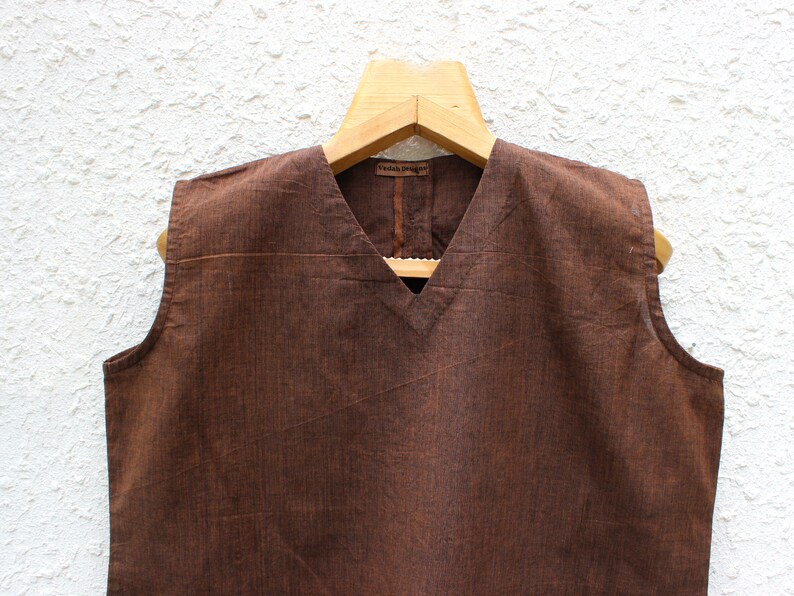 May include: A brown sleeveless top with a V-neckline. The top is made of a textured fabric and has a simple design.
