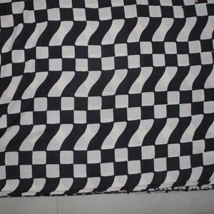 May include: A textile fabric featuring a repeating geometric pattern of black and white squares arranged in a grid. The design alternates between solid black squares and white squares that contain a subtle, repeating wavy or chevron-like texture.