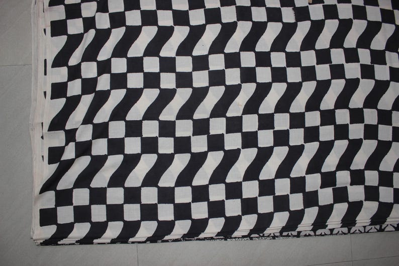 May include: A textile fabric featuring a repeating geometric pattern of black and white squares arranged in a grid. The design alternates between solid black squares and white squares that contain a subtle, repeating wavy or chevron-like texture.
