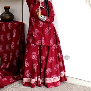 May include: A maroon-colored, long-sleeved shirt and skirt set with a paisley print. The shirt has a button-up front and the skirt is full-length.