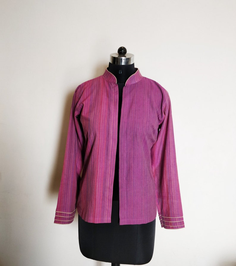 Puede incluir: Una chaqueta de manga larga de rayas rosas con cuello mandar&iacute;n y ribetes dorados. La chaqueta est&aacute; abierta por delante y tiene un corte holgado.