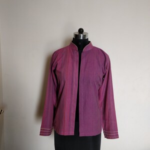 Puede incluir: Una chaqueta de manga larga, de rayas moradas y rosas, con cuello mandar&iacute;n y abertura frontal. La chaqueta tiene un brillo sutil y est&aacute; ribeteada con un fino borde de color crema.