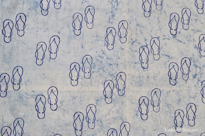 Pode incluir: Um tecido estampado em azul claro e branco com um desenho repetido de chinelos azuis escuros. O padr&atilde;o de chinelos est&aacute; espalhado pelo tecido, criando uma est&eacute;tica de ver&atilde;o e com tema de praia.