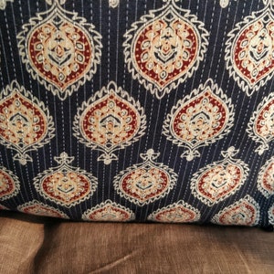 May include: A dark blue throw pillow with a white and brown paisley pattern. The pillow is quilted with white stitching.