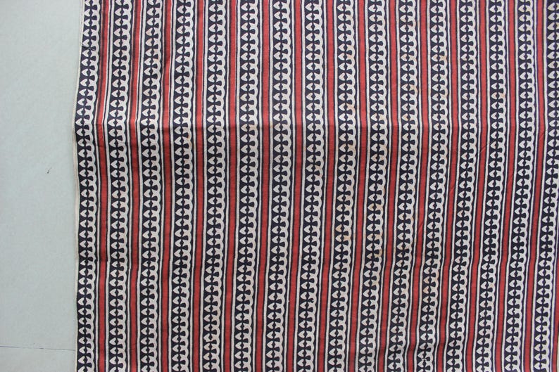 May include: A textile fabric featuring a repeating vertical pattern of alternating dark navy blue and deep red stripes. The navy blue stripes contain a white geometric chain-link motif, while the red stripes are solid and separated by thin white lines.