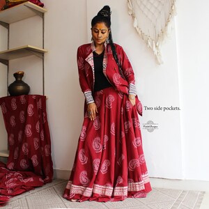 May include: A red and white paisley print skirt and matching jacket with a black inner lining. The skirt has two side pockets. The text "Two side pockets." is visible in the image.