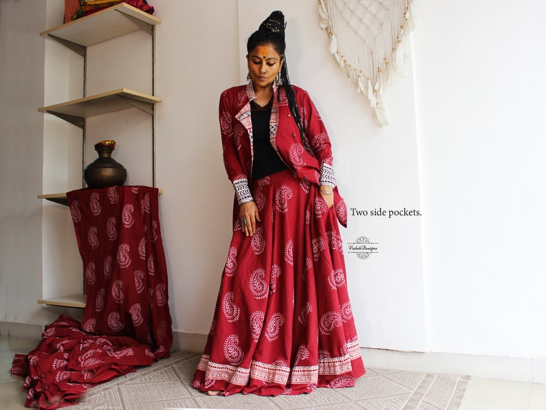 May include: A red and white paisley print skirt and matching jacket with a black inner lining. The skirt has two side pockets. The text "Two side pockets." is visible in the image.