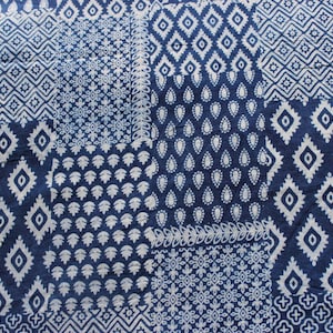 May include: Close-up of a textile with a patchwork design. The fabric has a navy blue background with white geometric patterns, including diamonds, paisley shapes, and floral motifs. The overall aesthetic is a blend of traditional and modern styles.