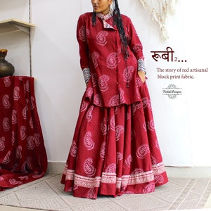 May include: A woman wears a red and white paisley print top and skirt. The top has a collar and long sleeves. The skirt is long and flowing. The text "खबी... The story of red artisanal block print fabric." is visible in the image.