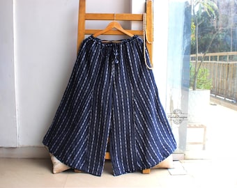 May include: Wide-leg trousers in a deep navy blue fabric featuring a vertical white pinstripe pattern. The pants have an elasticized waistband with a drawstring tie closure. A small logo with the text Vedah Designs is visible on the right side.
