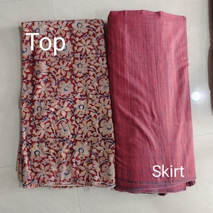 Puede incluir: Un conjunto de tela de dos piezas con una parte superior y una falda. La parte superior tiene un fondo rojo con un estampado floral en crema, amarillo y azul. La falda es de color rojo liso, con la palabra "Skirt" impresa.