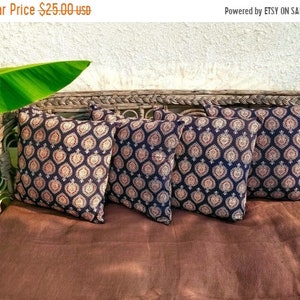 May include: Four black and cream patterned throw pillows with a geometric design. The pillows are arranged on a brown wicker couch.