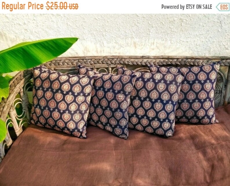 May include: Four black and cream patterned throw pillows with a geometric design. The pillows are arranged on a brown wicker couch.