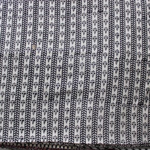 May include: A textile fabric featuring a repeating pattern of vertical black stripes alternating with rows of small black floral motifs on a white background. The design consists of a herringbone-style chevron stripe next to a column of stylized flowers.
