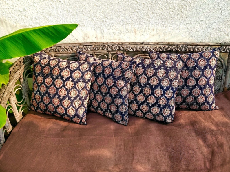 May include: Four decorative throw pillows with a black and white geometric pattern. The pillows are arranged on a brown couch with a woven wicker frame.