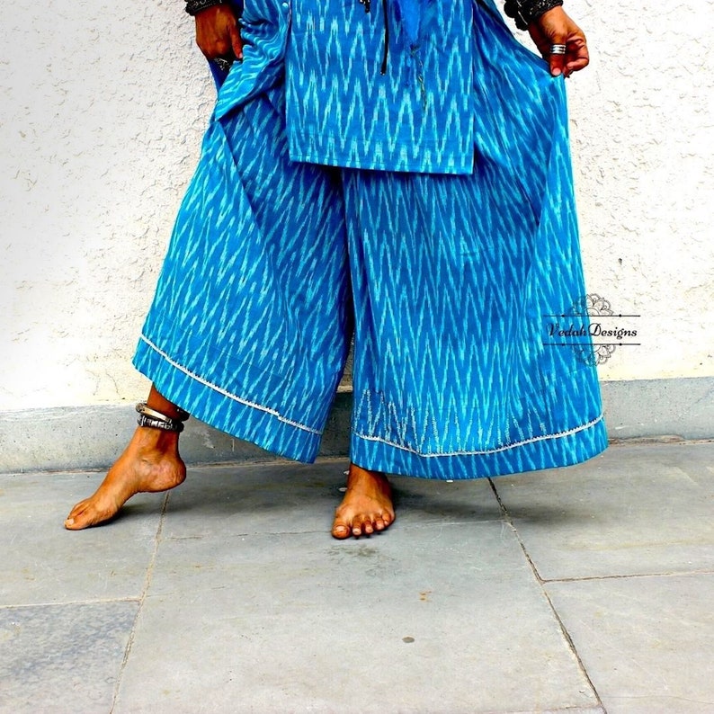 K&ouml;nnte beinhalten: Eine blaue Palazzo-Hose mit einem wei&szlig;en Ikat-Muster und wei&szlig;em Besatz. Die Hose ist weit geschnitten und flie&szlig;end.