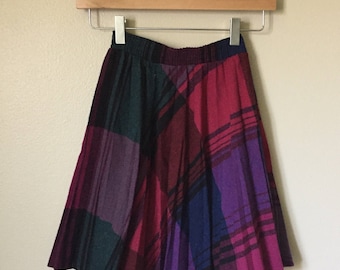 May include: A pleated skirt with a plaid pattern in shades of purple, red, green, and black.