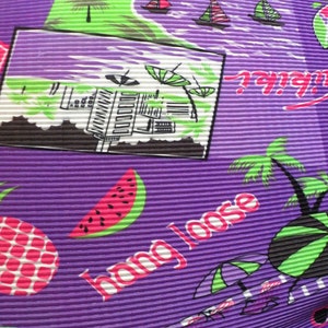 May include: Purple fabric with a tropical print featuring palm trees, watermelons, pineapples, and the text "Hang Loose".