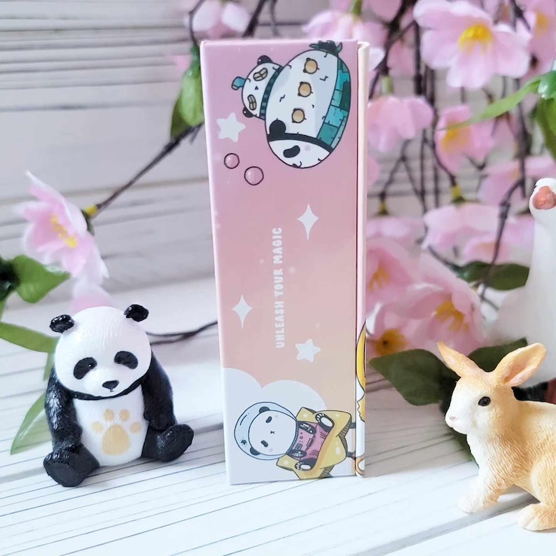 May include: A pink and yellow box with a cartoon panda wearing a space helmet and a spaceship. The box says "Unleash Your Magic".
