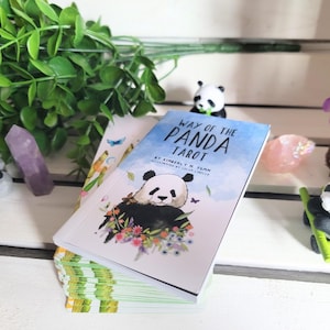 May include: A blue and white tarot deck with a panda illustration on the front. The deck is titled "Way of the Panda Tarot" by Kimberly M. Tsan. The deck is illustrated by Celine Libelle.