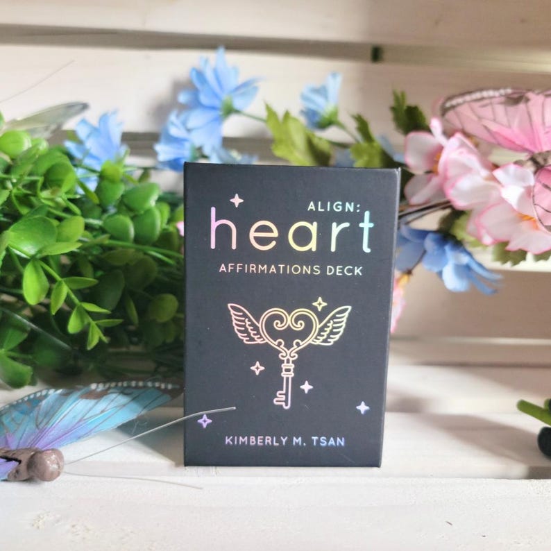 May include: A black box with the words "ALIGN: heart AFFIRMATIONS DECK" and "KIMBERLY M. TSAN" printed on it. The box features a colorful illustration of a heart with wings and a key.
