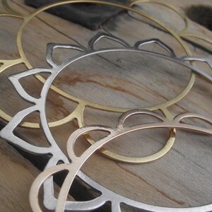 May include: Two metal hoops, one gold and one silver, with a decorative scalloped edge. The hoops are stacked on top of each other.