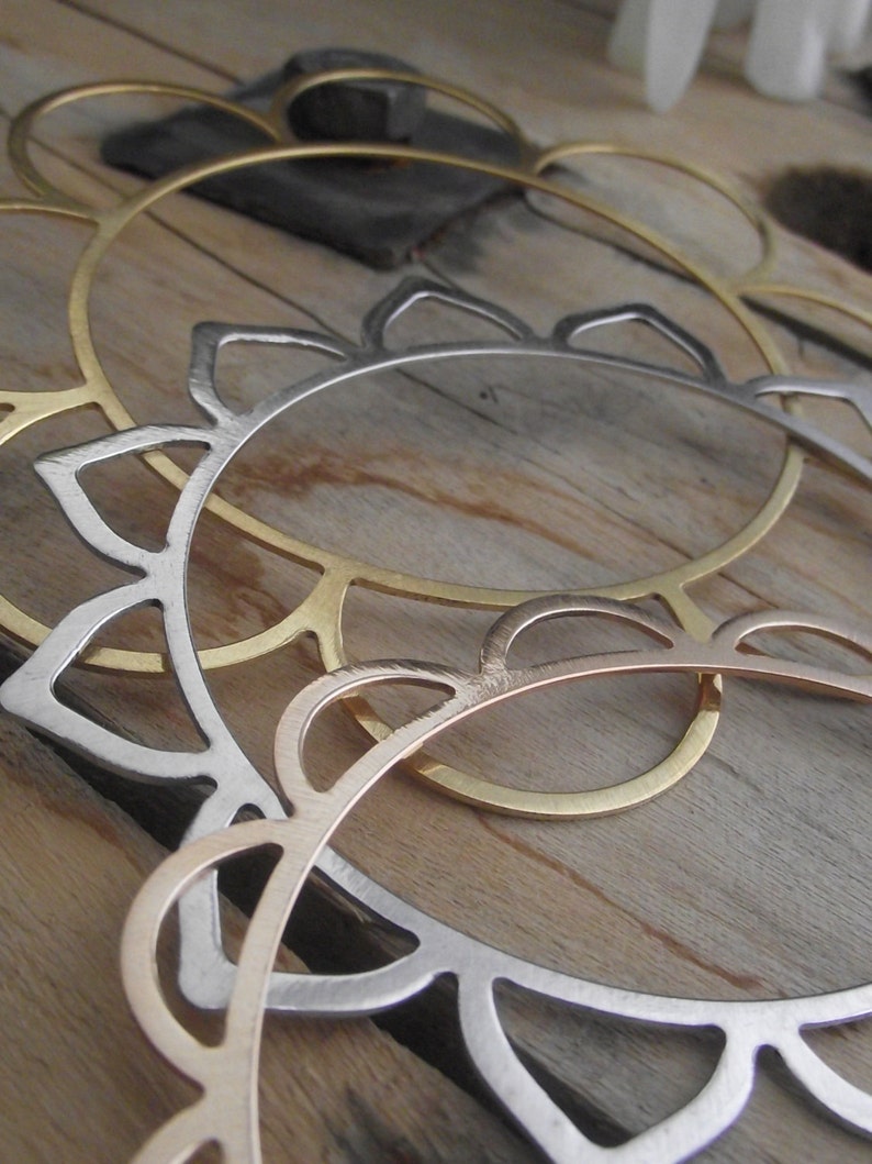 May include: Two metal hoops, one gold and one silver, with a decorative scalloped edge. The hoops are stacked on top of each other.