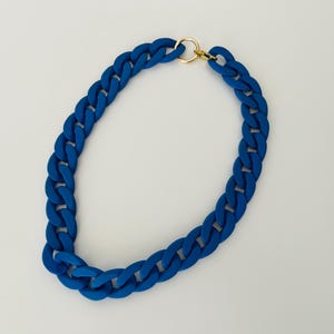 May include: A thick, blue chain necklace with a gold clasp. The chain is made of a chunky, rubber-like material.