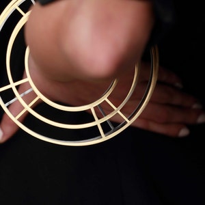 Puede incluir: Un aro de oreja geom&eacute;trico de oro y plata con un dise&ntilde;o circular.