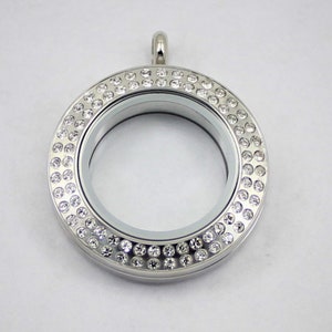 May include: A silver locket with a round, clear glass insert and a border of small, clear rhinestones.