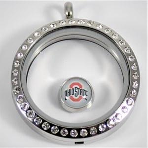 May include: Silver locket with a clear glass insert and a crystal-encrusted border. The locket features a small charm with the Ohio State logo.