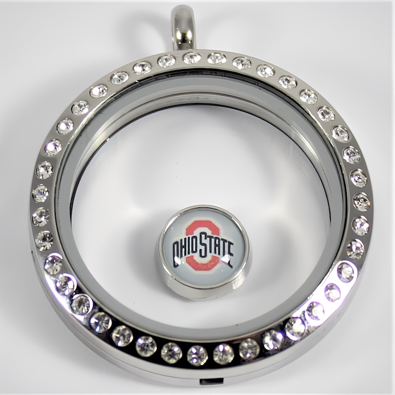 May include: Silver locket with a clear glass insert and a crystal-encrusted border. The locket features a small charm with the Ohio State logo.