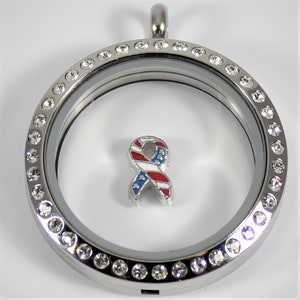 May include: Silver locket necklace with a clear glass insert and a small American flag ribbon charm. The locket is surrounded by a row of clear rhinestones.