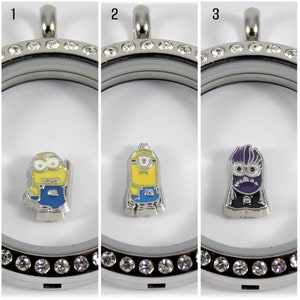 May include: Three silver locket necklaces with clear crystal accents. Each locket contains a different character from the Despicable Me franchise. The first locket contains a yellow minion with blue overalls. The second locket contains a yellow minion with blue overalls. The third locket contains a purple minion with a black suit.