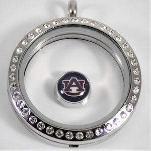 May include: Silver locket necklace with a clear glass insert and a round charm with the Auburn University logo. The locket is decorated with clear rhinestones.